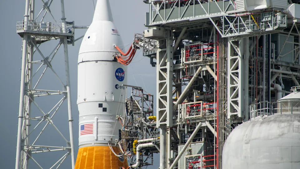An orange rocket with a white top stands against a dynamic sky.